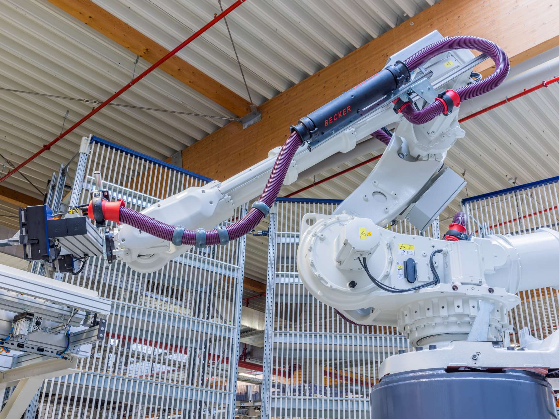 A large white robot arm stands in a factory hall