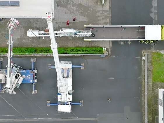 Bird's eye view of the delivery of the edging and formatting cells at the Stiegelmeyer plant in Nordhausen. An element is being lifted from a truck by two crane trucks.